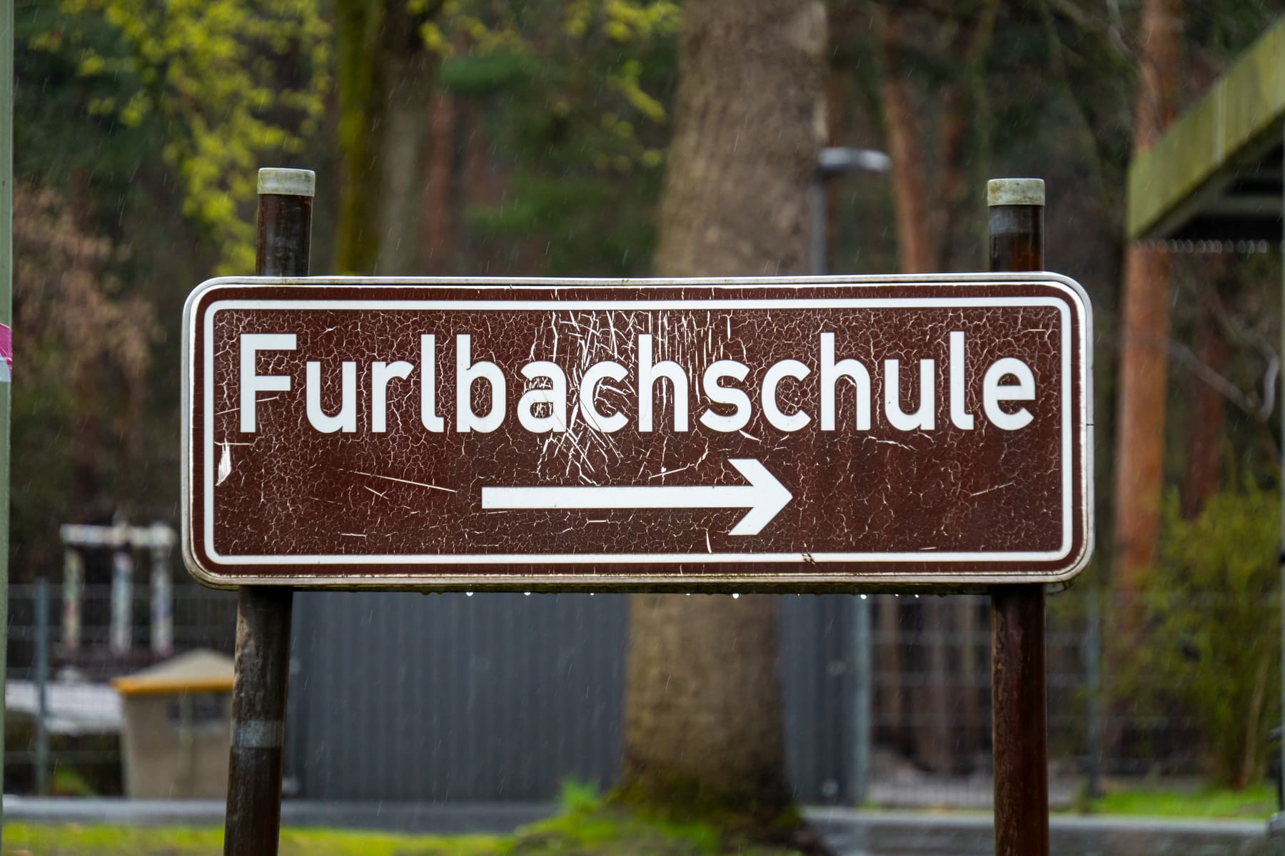 Braunes Hinweisschild Furlbachschule im Regen