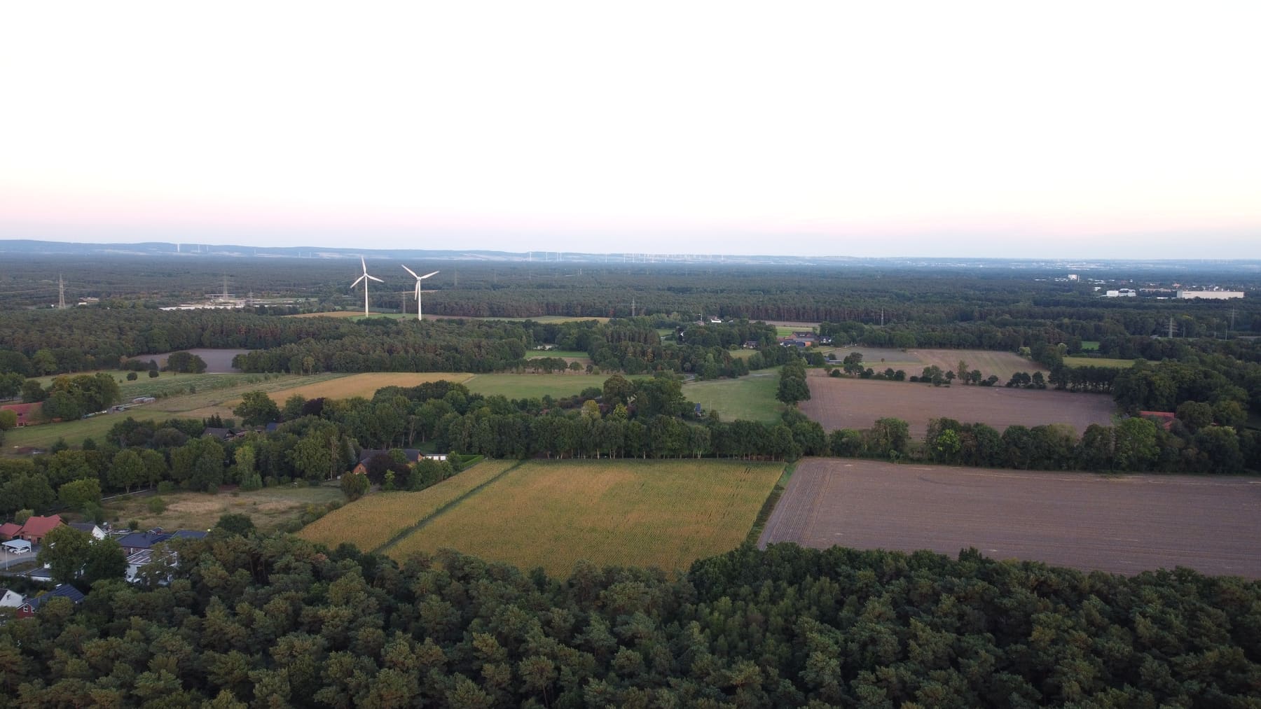 Weiter Blick über Felder und Wälder mit Windrädern im Abendlicht